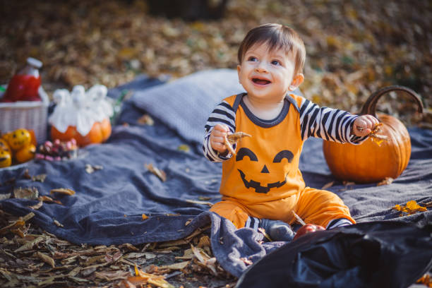 A smiling 6-month-old baby dressed in a plush animal costume sitting in a pumpkin patch.