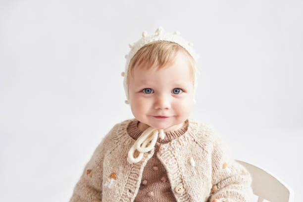 Baby in a soft cotton cardigan sitting on a blanket.
