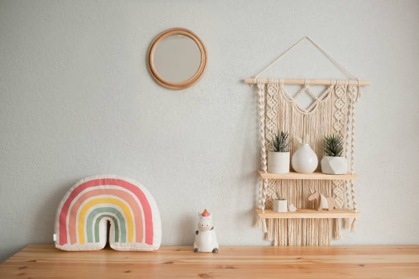 A cozy baby room wall with framed animal prints, soft wall hangings, floating shelves with toys, and a pastel rainbow mural.