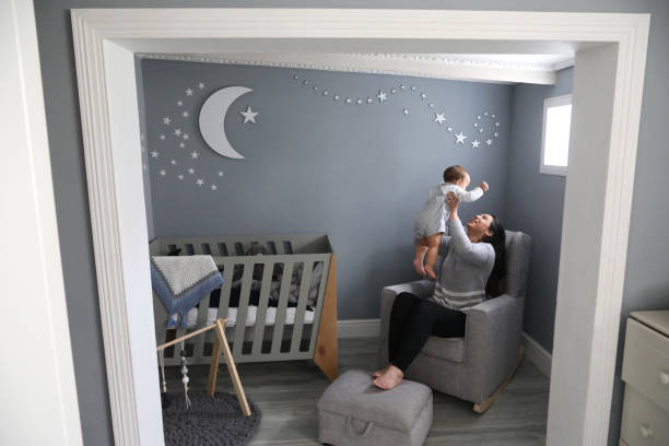 A mother playing with her 11-month-old son in the nursery at home.