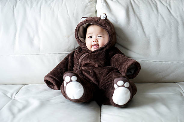 Baby dressed in a plush animal costume sitting on a blanket.