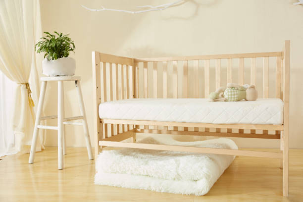 Crib mattress with a white, waterproof mattress protector in a cozy nursery setting.