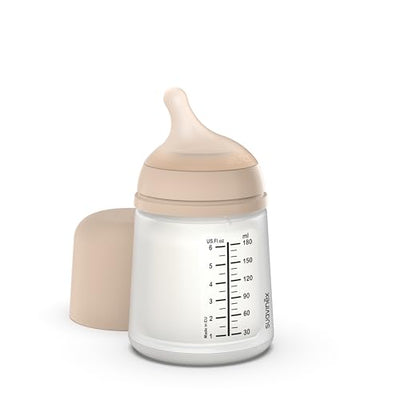 Baby bottle with beige cap and measurement markings on a white background