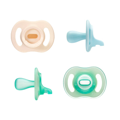 Four pacifiers in different colors on a white background