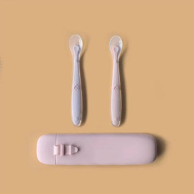 Two baby spoons with a pink case on a beige background