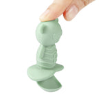 Green silicone teether held by a hand on a white background