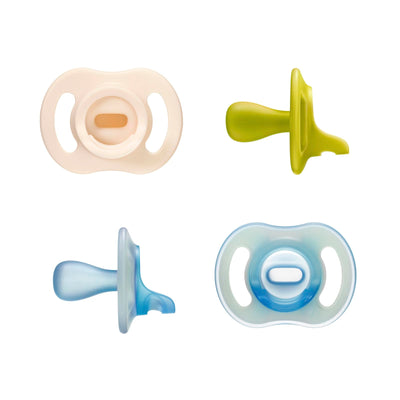 Four baby pacifiers in different colors on a white background