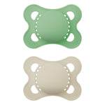 Two silicone pacifiers, one green and one beige, on a white background.