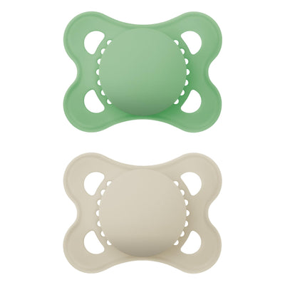 Two silicone pacifiers, one green and one beige, on a white background.