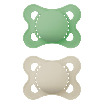 Two silicone pacifiers, one green and one beige, on a white background.