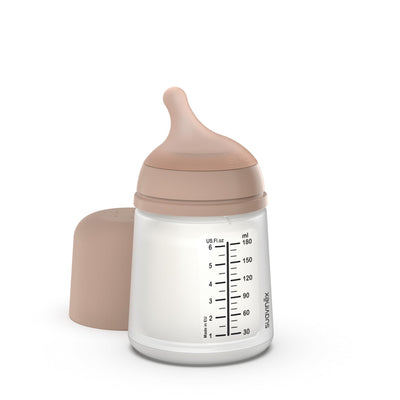 Baby bottle with pink cap and measurement markings on a white background