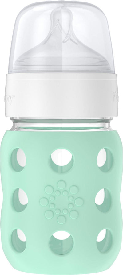 Mint green baby bottle with white cap on a light gray background