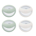 Four round containers with green and white lids on a white background