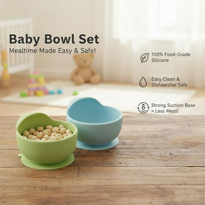 Two baby bowls, one green and one blue, on a wooden surface with a baby's crib and toys in the background.