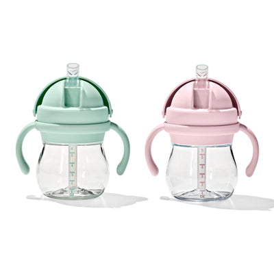 Two baby sippy cups, one green and one pink, on a white background.