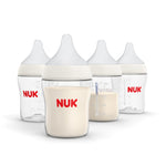 Four NUK baby bottles with white liquid on a white background