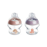 Two baby bottles with pink and purple caps on a white background
