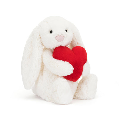 White plush bunny holding a red heart on a white background