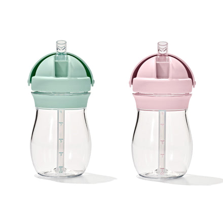 Two clear sippy cups with green and pink lids on a white background
