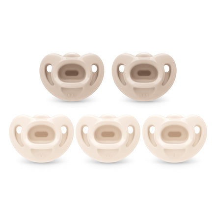 Set of five beige baby pacifiers on a white background