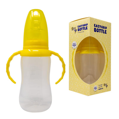 Clear baby bottle with yellow lid and handles next to its packaging on a white background