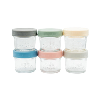 Set of four clear glass jars with colorful lids on a white background