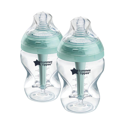 Two Tommee Tippee baby bottles with green caps on a white background