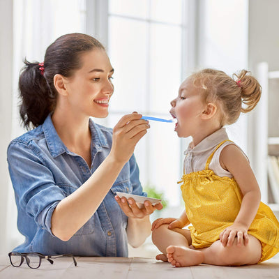 Woman feeding a child with a spoon in a bright room