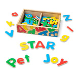 Colorful wooden alphabet letters scattered around a wooden box on a white background