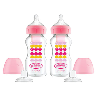 Two Dr. Brown's baby bottles with pink caps and heart patterns on a white background