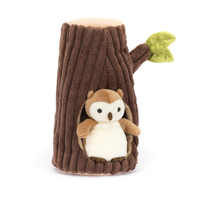 Plush owl toy inside a tree stump on a white background