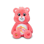 Pink plush bear with a white belly featuring cartoon faces and a heart on a white background