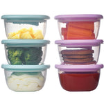Set of clear food storage containers with colorful lids containing various vegetables and cookies.