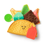 Toy taco set with smiling face, tortilla, lettuce, tomato, and lime on a white background