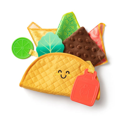 Toy taco set with smiling face, tortilla, lettuce, tomato, and lime on a white background