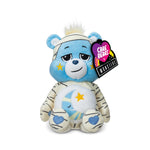 Plush toy bear with blue face and white body, wearing a bandage, on a white background with 'Care Bears' tag.