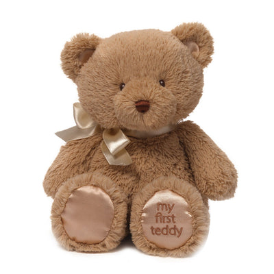 Brown teddy bear with a gold bow and 'my first teddy' text on a white background
