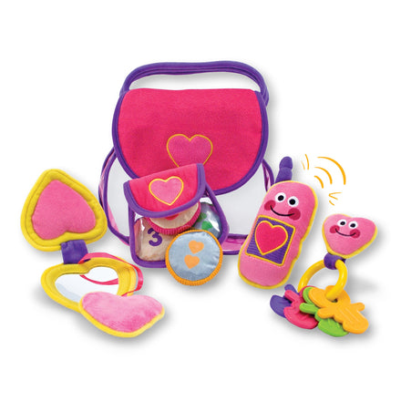 Colorful toy set with a pink bag, plush toys, and rattles on a white background