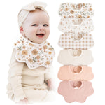 Baby wearing a floral bib with a stack of similar bibs on a white background