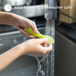 Person washing a green spoon under running water with text 'easy to clean, dishwasher safe' above.