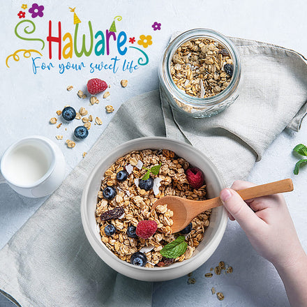 Bowl of granola with berries and a jar of granola on a light gray cloth, with 'Haware' branding.